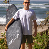 Fun Day Surf Aloha Tee in White worn with a surfboard at the beach, lifestyle view
