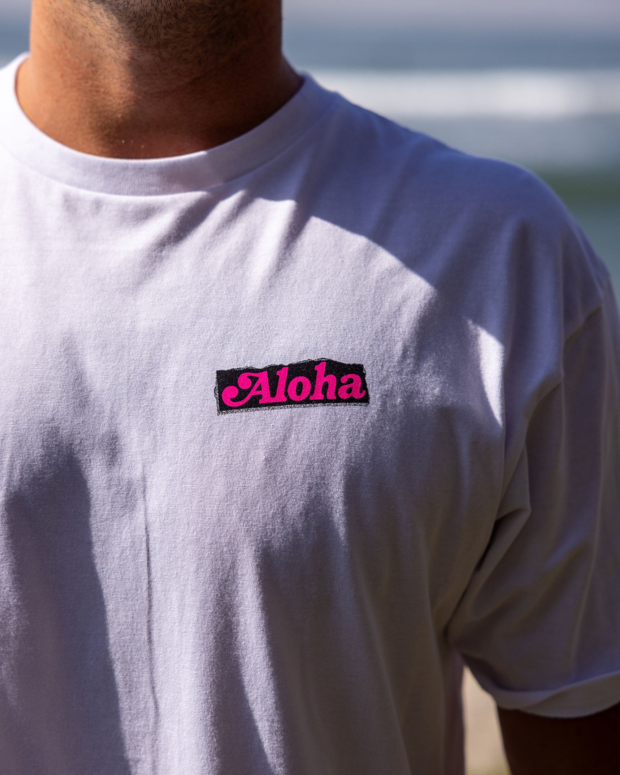 Fun Day Surf Aloha Tee in White chest print close-up, lifestyle view