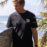 Fun Day Surf DFTF Tee in Black worn with a surfboard at the beach, lifestyle view