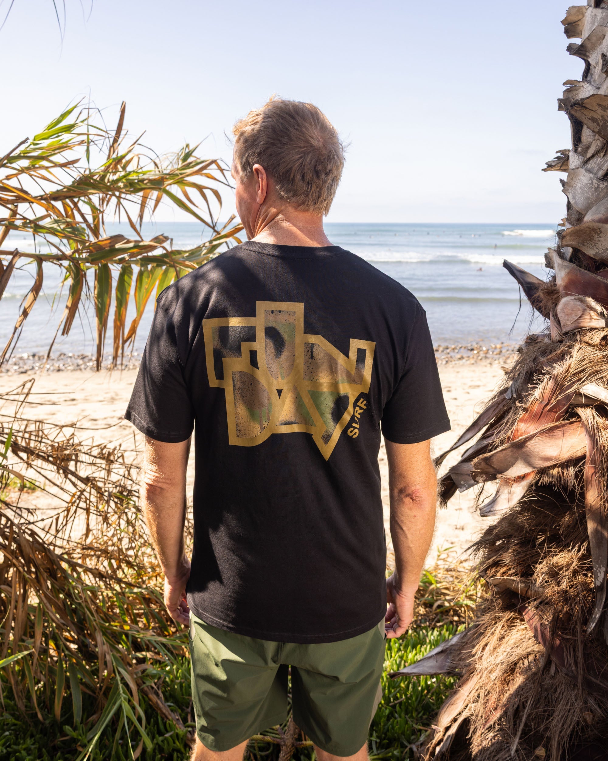 Fun Day Surf Framework Fill Tee in Black back graphic worn at the beach, lifestyle view