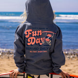 Fun Day Surf Musubi Youth Hoodie in Steel Blue back graphic worn holding a surfboard at the beach, lifestyle view