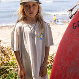 Fun Day Surf Stay Cool Youth Tee in Bone worn with a surfboard at the beach, lifestyle view